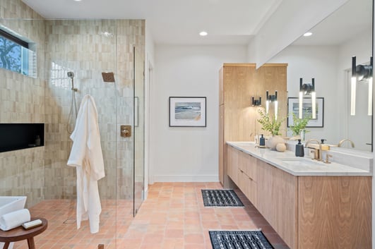 Earth-toned bathroom with natural tile and wood cabinetry in custom home in Austin, TX