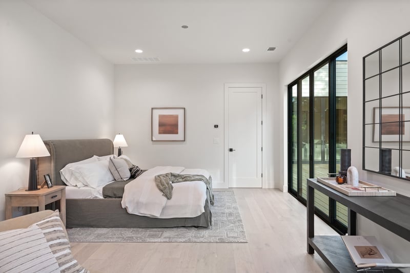 Minimalist bedroom design with sliding glass doors in custom home in Austin, TX