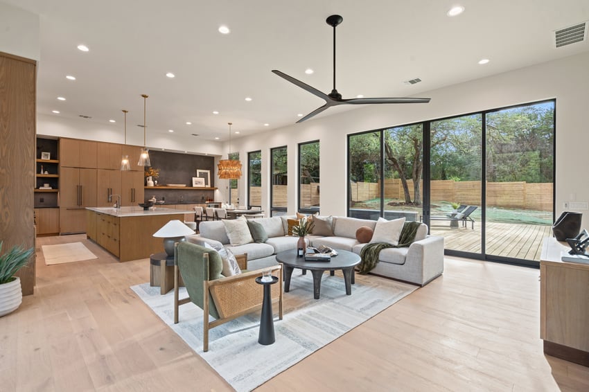 Open-concept living area with sectional and view of backyard in a custom home in Austin, TX by J. Angelo Design Build