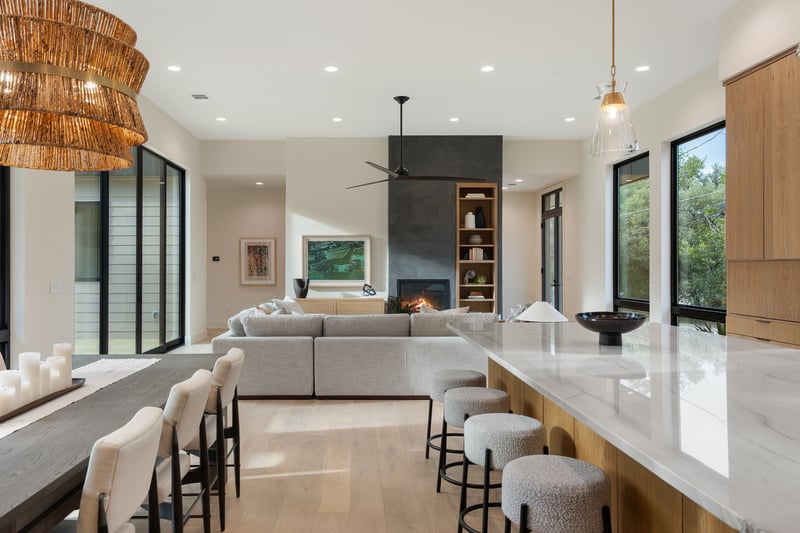 Spacious living area with fireplace and island seating in a custom home in Austin, TX by J. Angelo Design Build