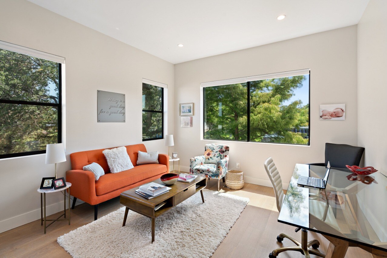 Remodeled office with orange couch and large windows by J. Angelo Design Build