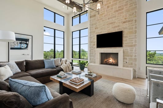 Living room with high ceilings, large windows, and stone fireplace in custom home by J. Angelo Design Build