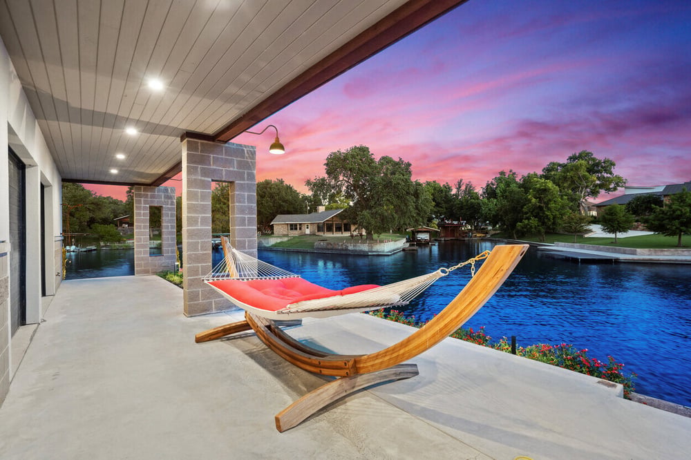 Serene lakeside patio with a wooden hammock stand at a custom home on Lake LBJ by J. Angelo Design Build in Austin, TX