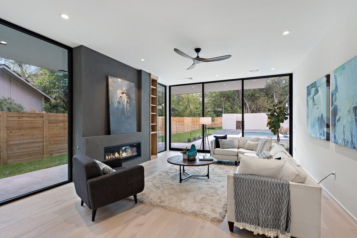 Interior of custom home living room featuring floor-to-ceiling sliding glass doors to backyard pool by J. Angelo Design build in Austin, TX
