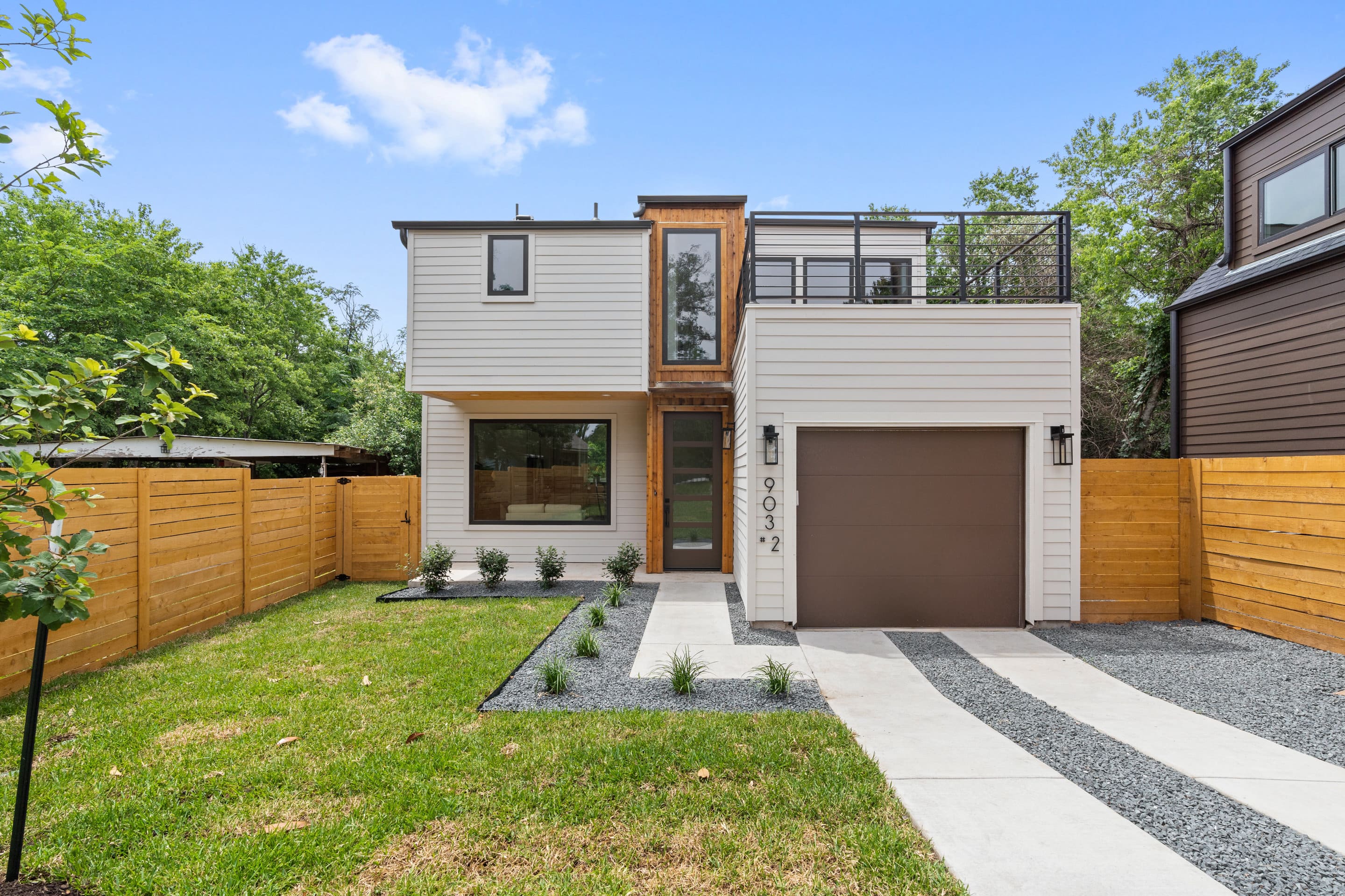 Exterior view of a custom built ADU in Austin, TX by J. Angelo Design Build featuring a rooftop garage deck, warm wood entryway, and large windows at front