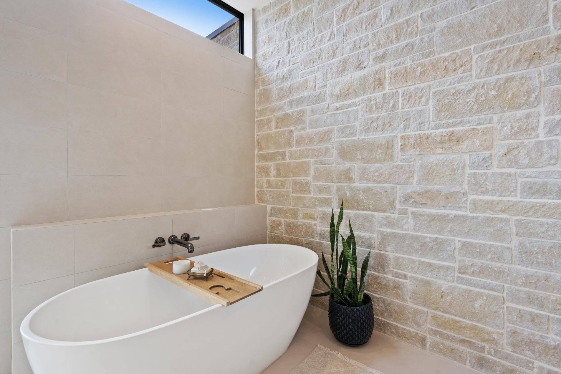 Custom master bathroom footless bathtub and brick wall in custom home by J. Angelo Design Build in Austin, Texas