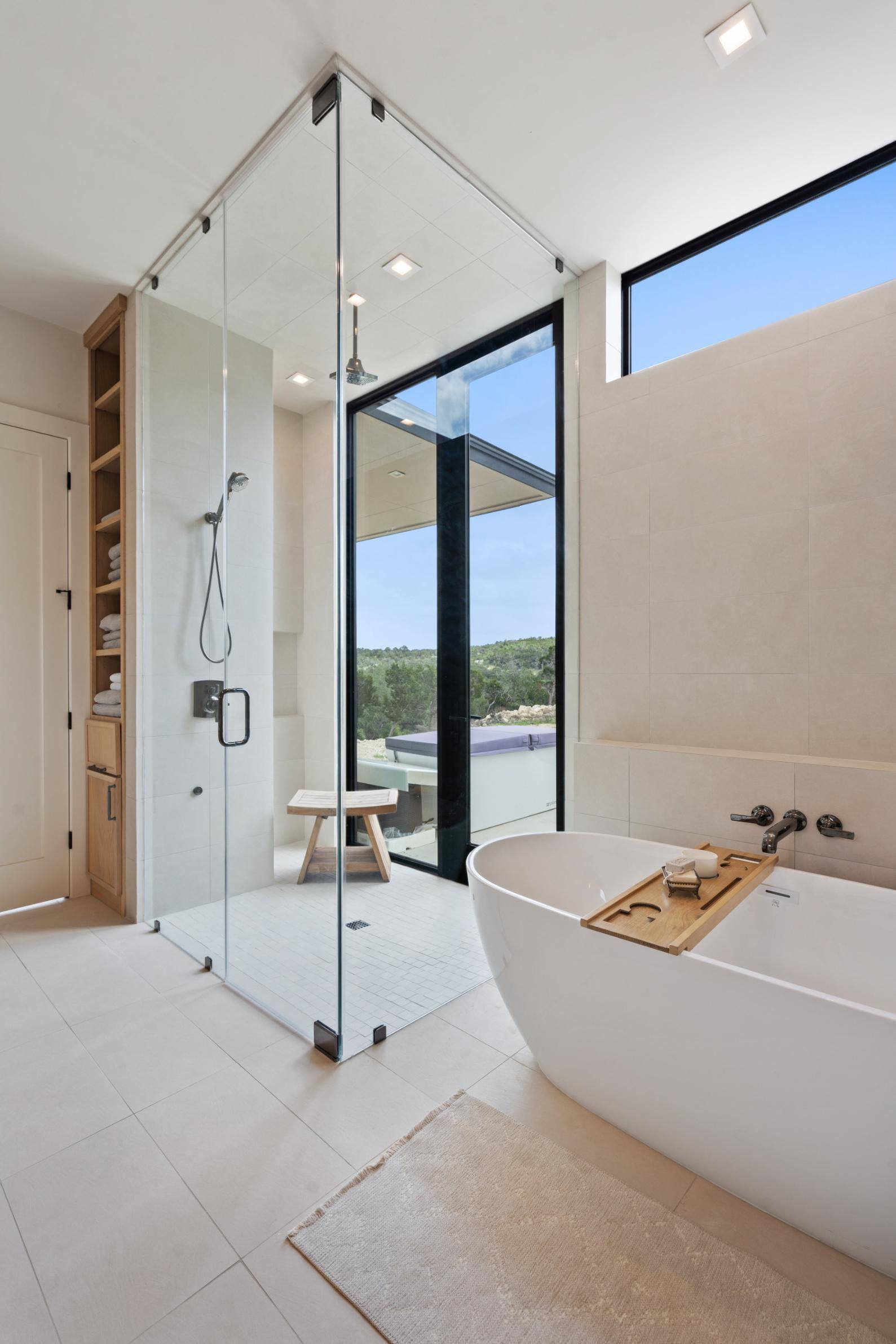 Custom home bathroom bright with natural light, walk-in shower and footless bathtub by J. Angelo Design Build in Austin, Texas