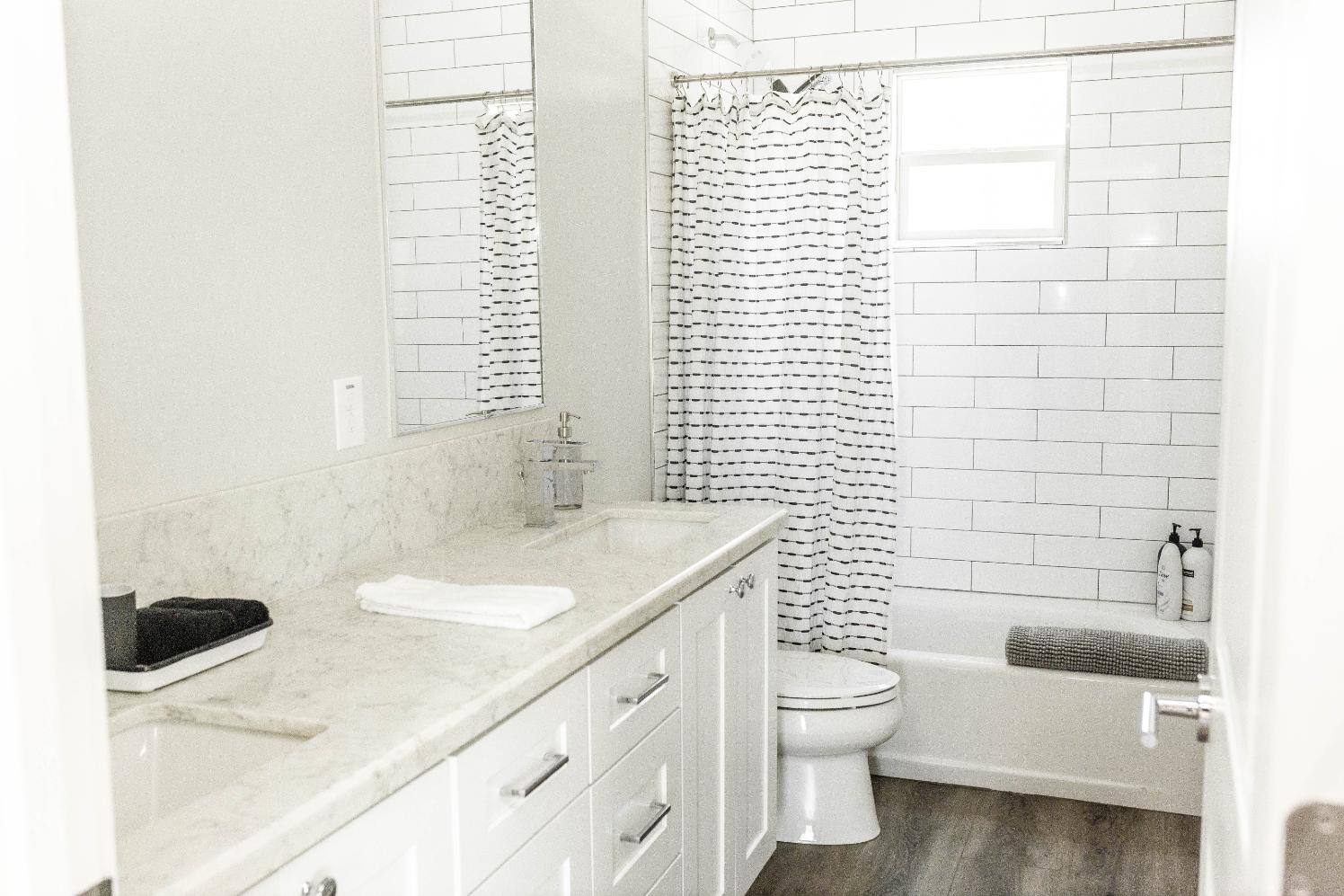 Remodeled bathroom with white tile shower by J. Angelo Design + Build