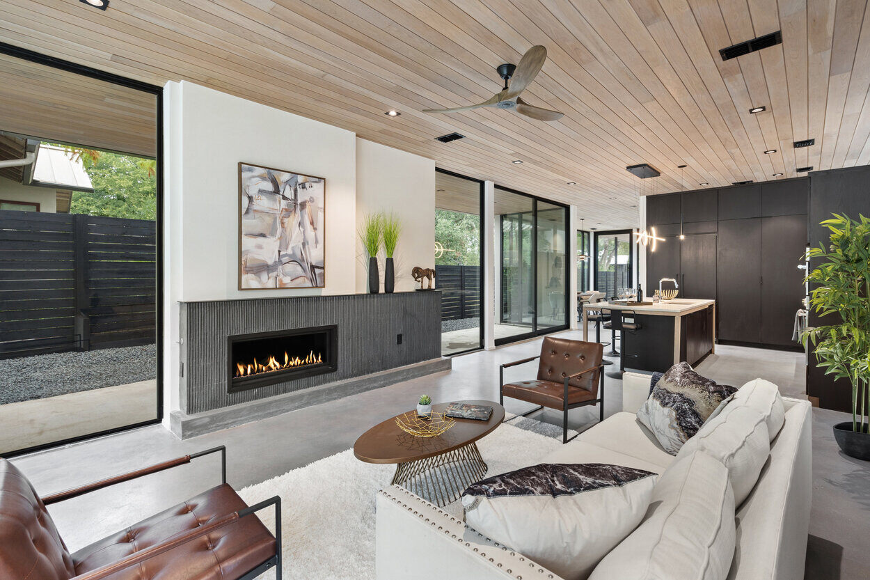 Cozy yet sophisticated living area featuring warm wood tones, glass walls, and a fireplace in a custom home in Austin, TX by J. Angelo Design Build