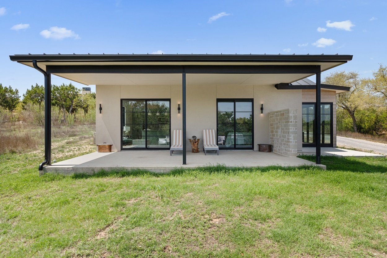 Back facade of a detached casita by J. Angelo Design Build in Austin, TX with dual lounge chairs and shaded patio