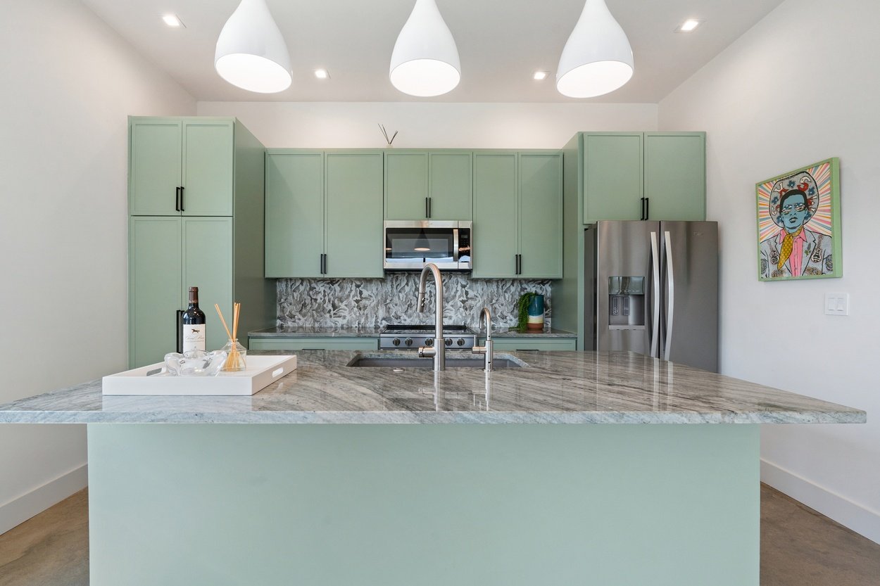 Close-up of sage green kitchen island with marble countertop in a detached casita by J. Angelo Design Build in Austin, TX