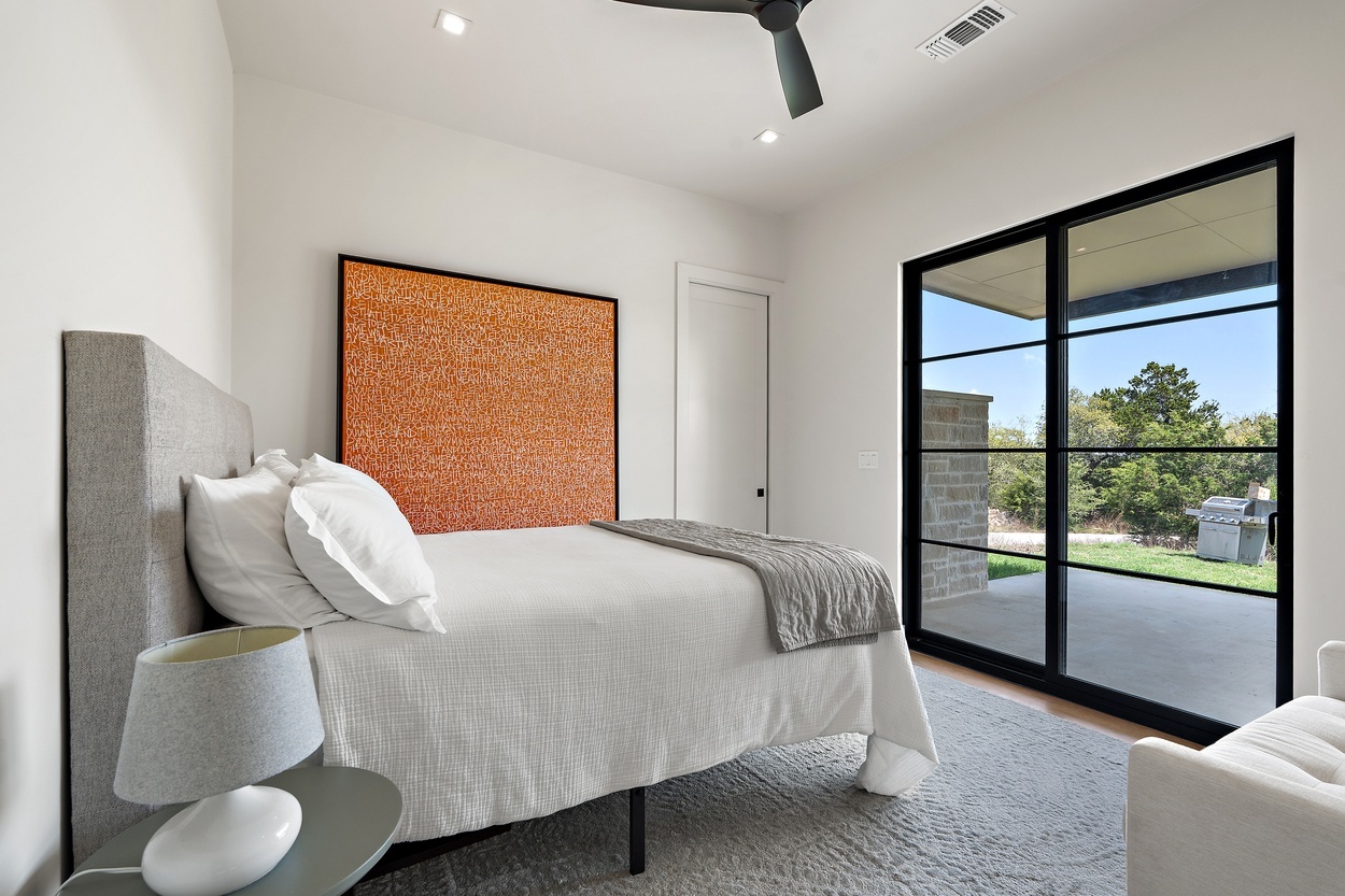 Contemporary bedroom with clean design and wall-mounted orange artwork in a detached casita by J. Angelo Design Build in Austin, TX