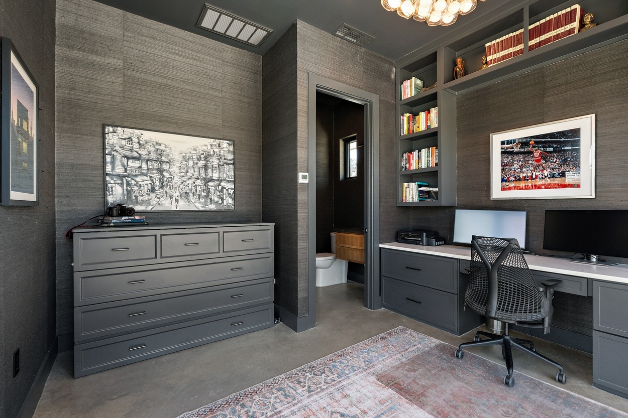 Contemporary office featuring workspace, wall art, and dark textured walls in a detached casita by J. Angelo Design Build in Austin, TX