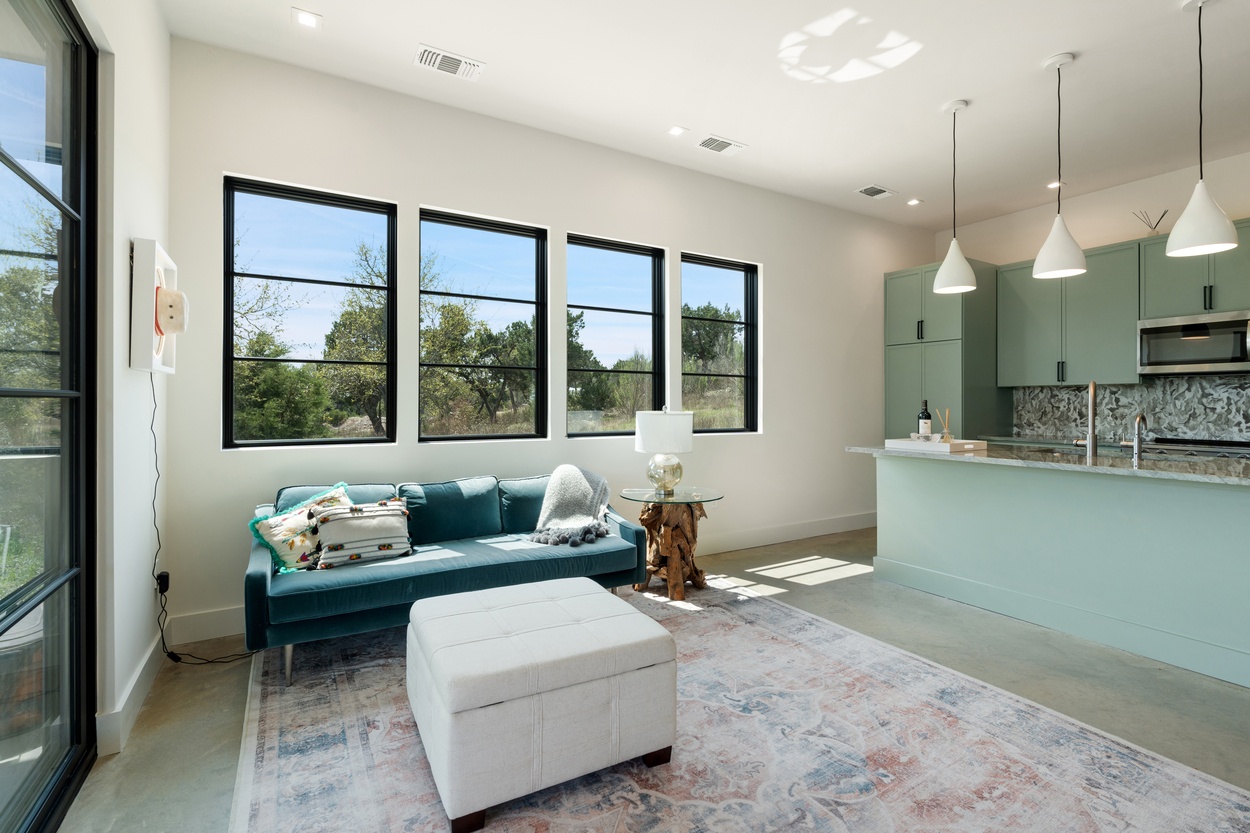 Daylit open-plan space with teal couch and modern kitchen in a detached casita by J. Angelo Design Build in Austin, TX
