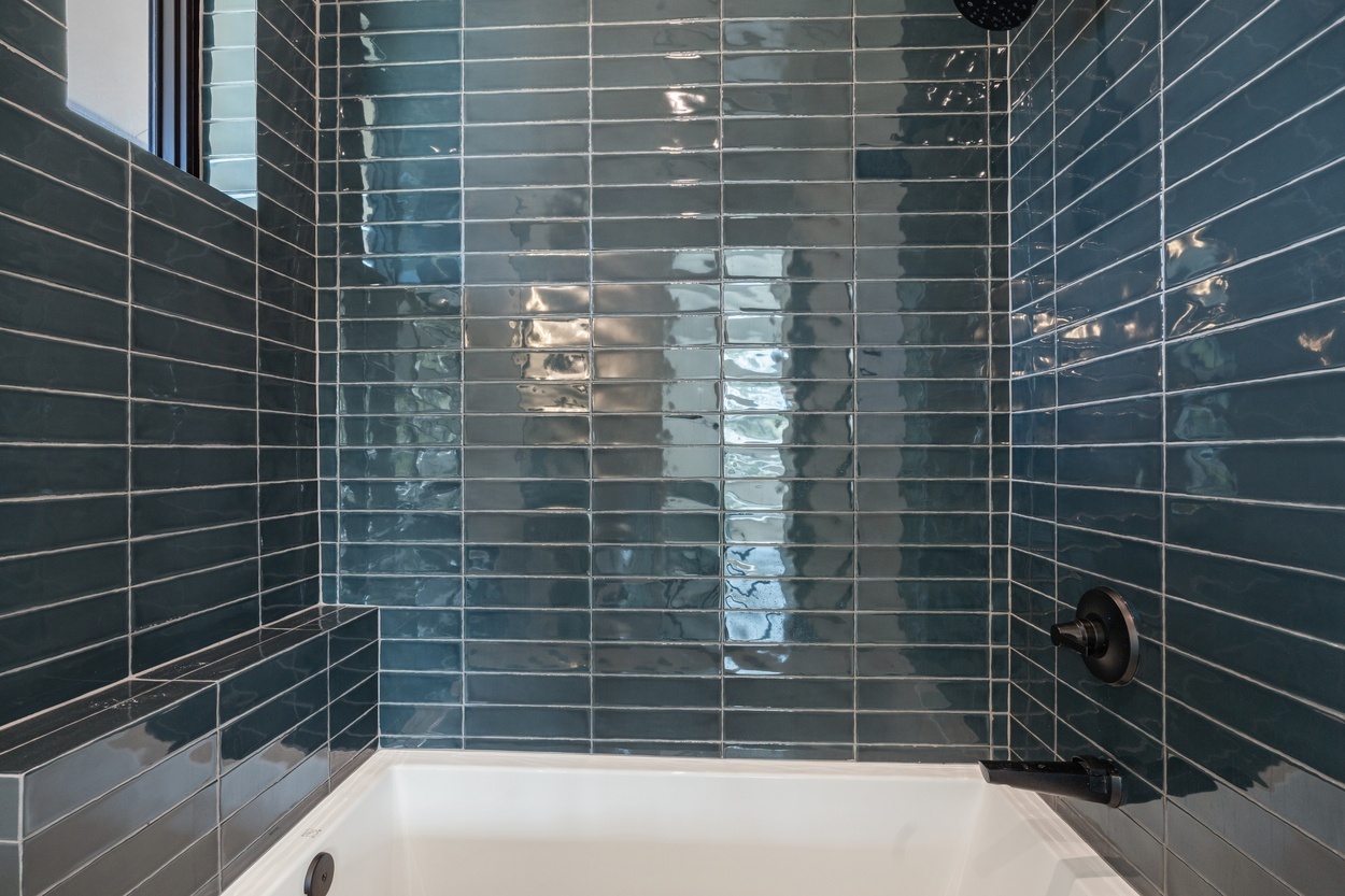 Detailed view of shower with glossy navy tile and black fixtures in a detached casita by J. Angelo Design Build in Austin, TX.