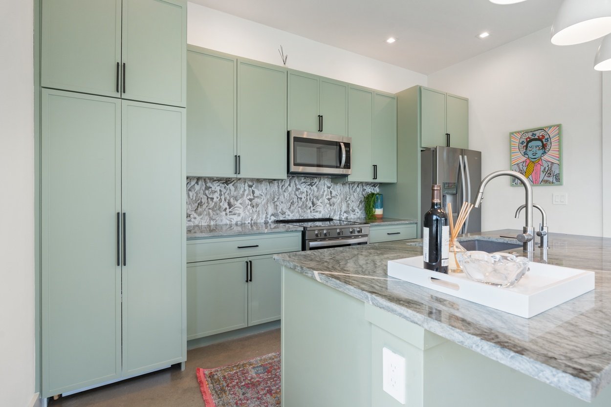 Kitchen with green cabinetry and wine tray on marble island in a detached casita by J. Angelo Design Build in Austin, TX