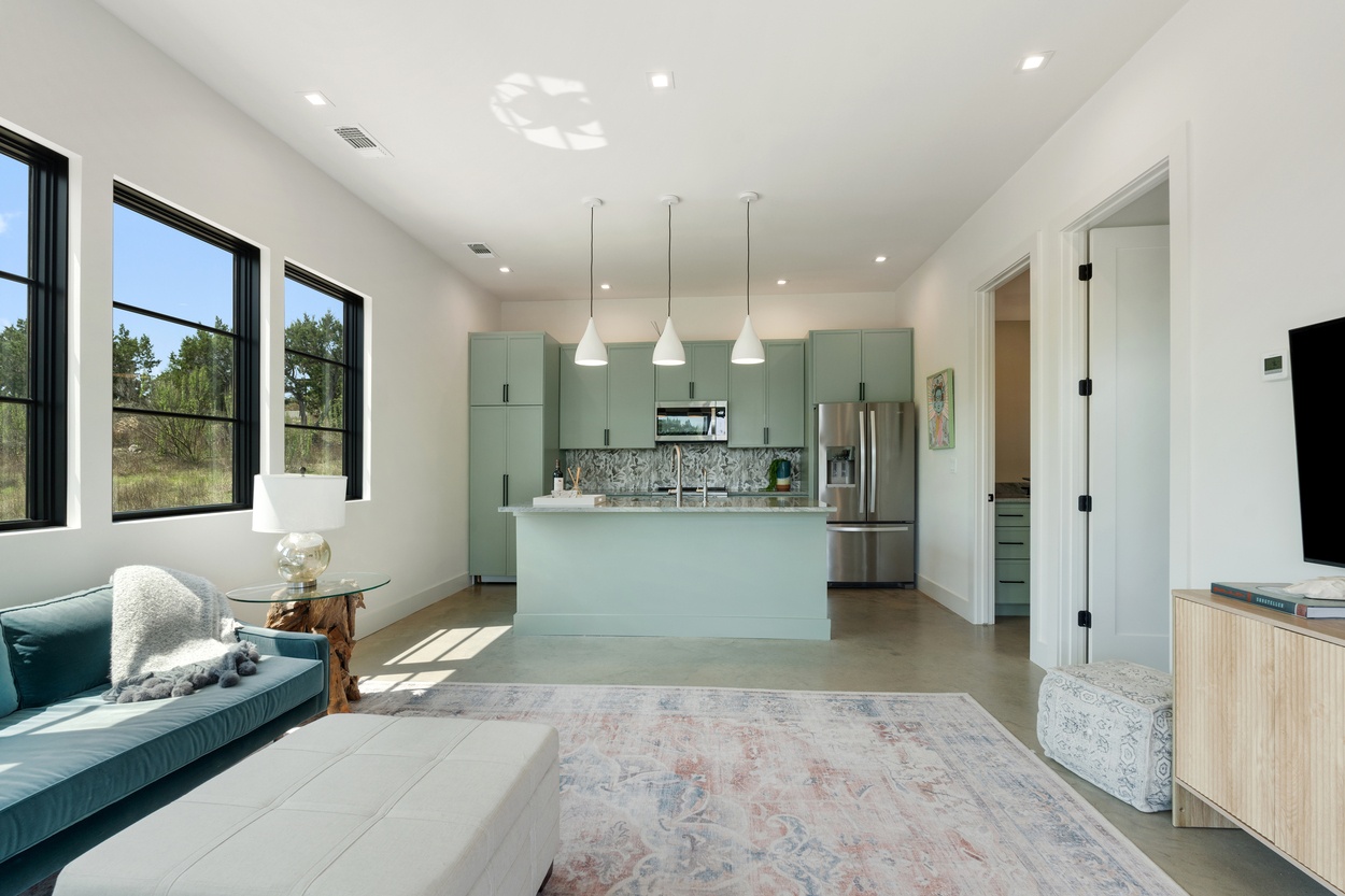 Open-concept kitchen and living space with sage green cabinets in a detached casita by J. Angelo Design Build in Austin, TX