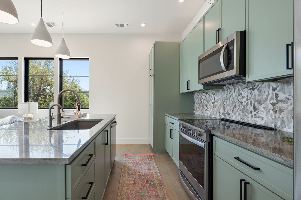 Sleek kitchen design with black hardware and pendant lighting in a detached casita by J. Angelo Design Build in Austin, TX
