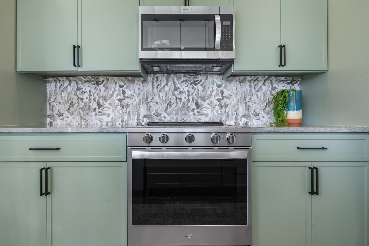 Stainless steel stove and microwave framed by custom cabinetry in a detached casita by J. Angelo Design Build in Austin, TX