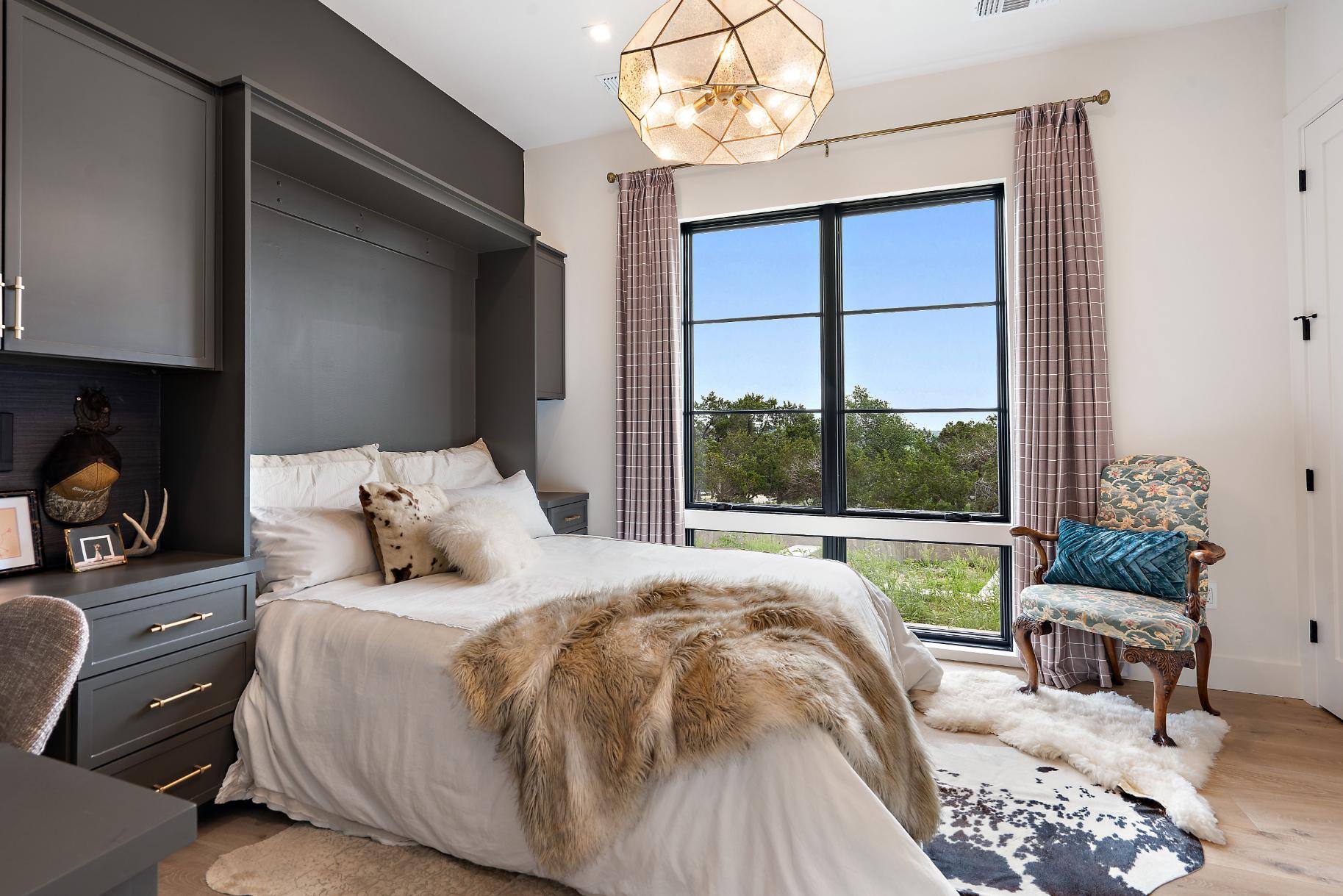 Bedroom with grey cabinetry and large window in custom home by J. Angelo Design Build in Southwest Austin, TX