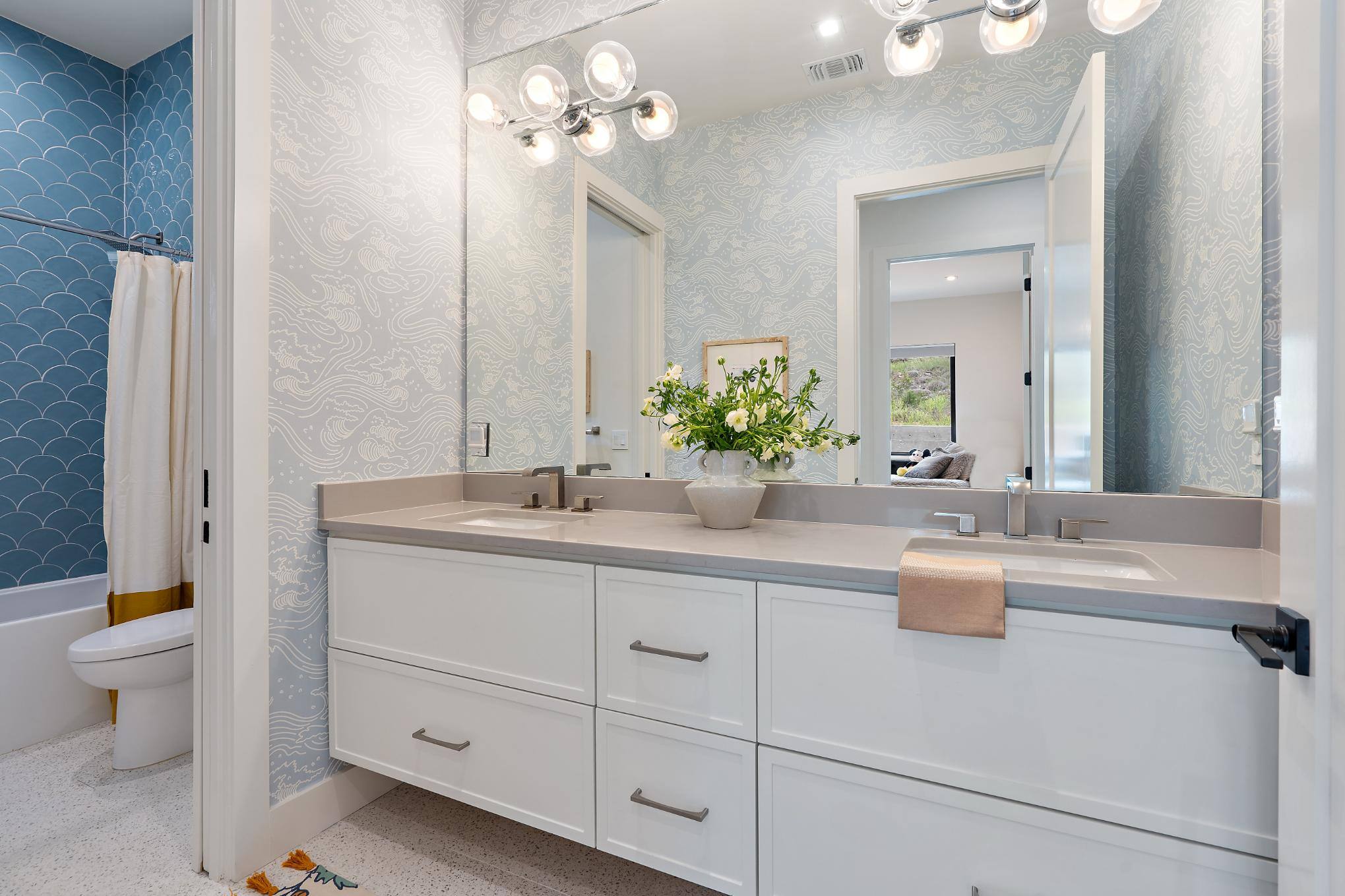 Elegant bathroom with dual sinks and floral arrangement in a custom home by J. Angelo Design Build in Southwest Austin, TX