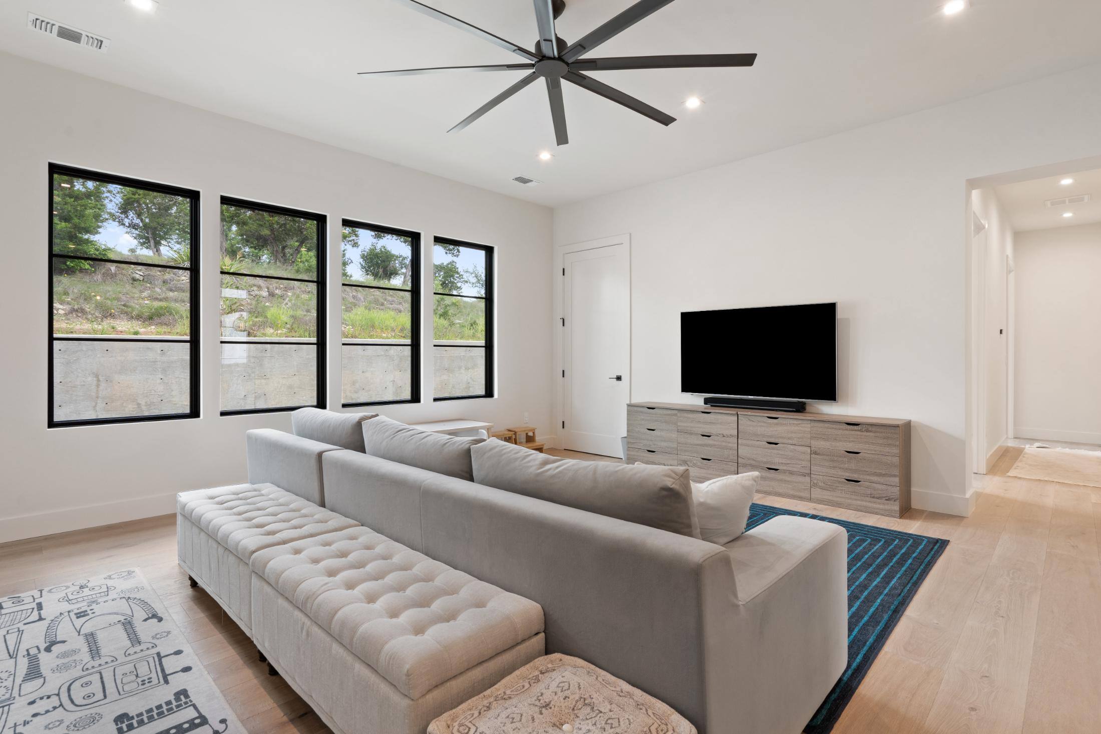 Entertainment room couch and television featuring 4 windows in custom home built in Austin, TX by J. Angelo Design Build