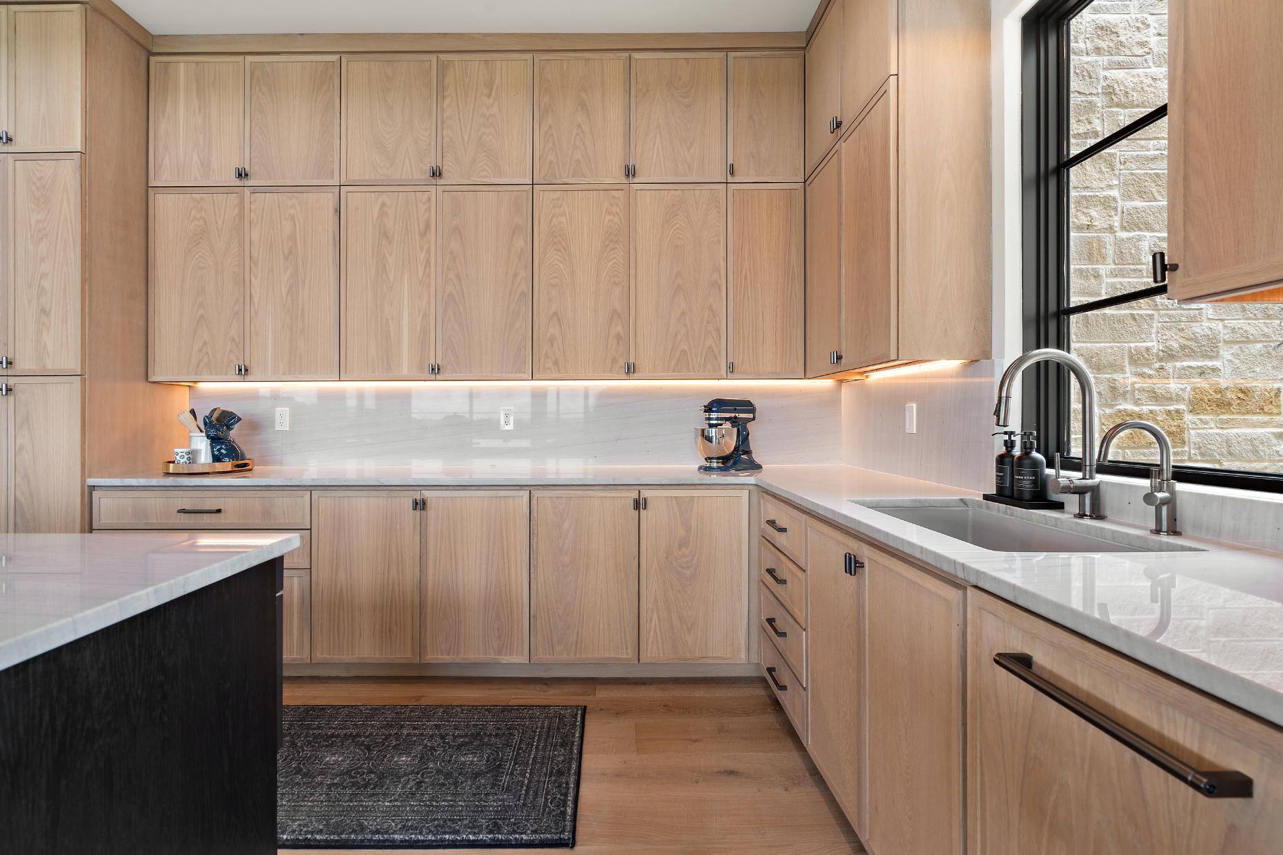 Kitchen area cabinetry, sink, and window in custom home by J. Angelo Design Build in Southwest Austin, TX