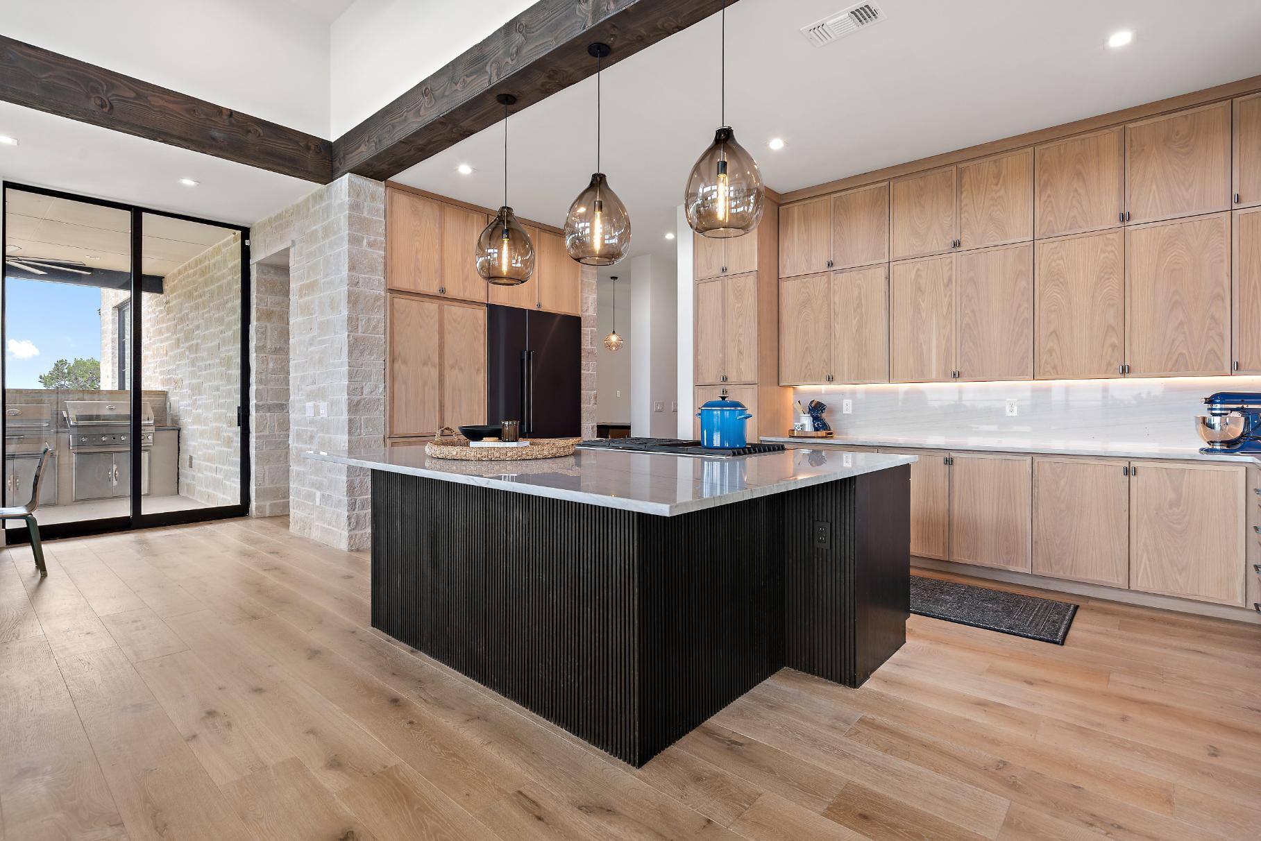 Kitchen area with partial view of outside porch area and large sliding glass doors in custom home by J. Angelo Design Build in Southwest Austin, TX