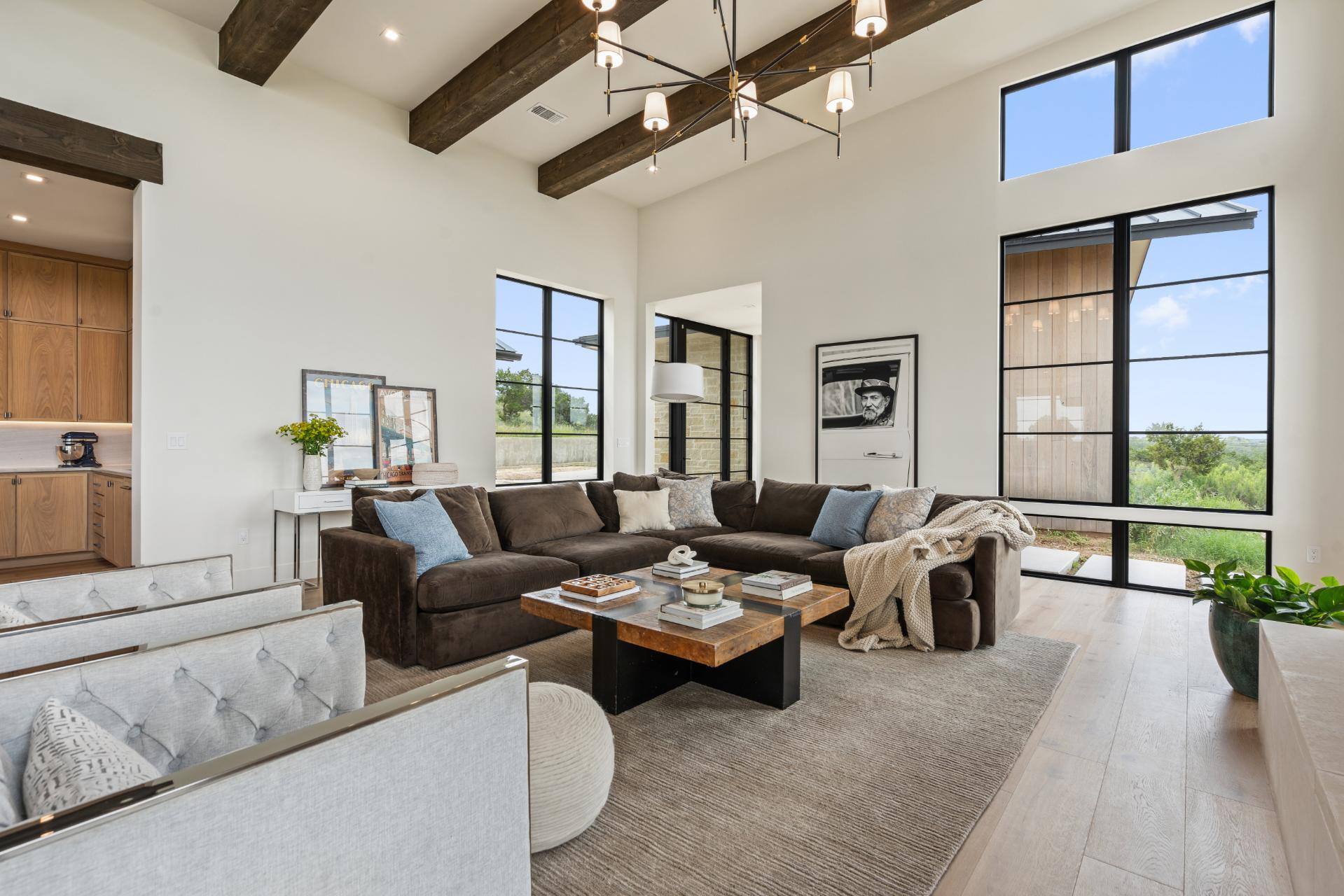 Living room couch beneath exposed beams and chandelier in custom home by J. Angelo Design Build in Southwest Austin, TX