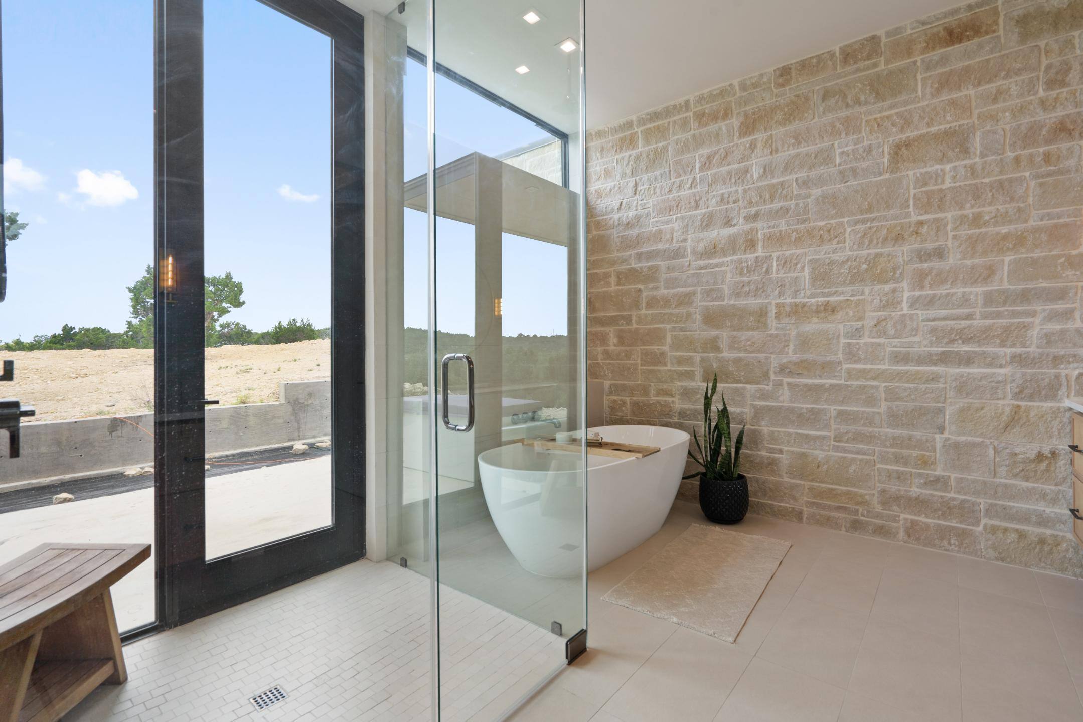 Master bathroom bathing area featuring walk-in shower with access to backyard and footless bathtub custom home by J. Angelo Design Build in Southwest Austin, TX