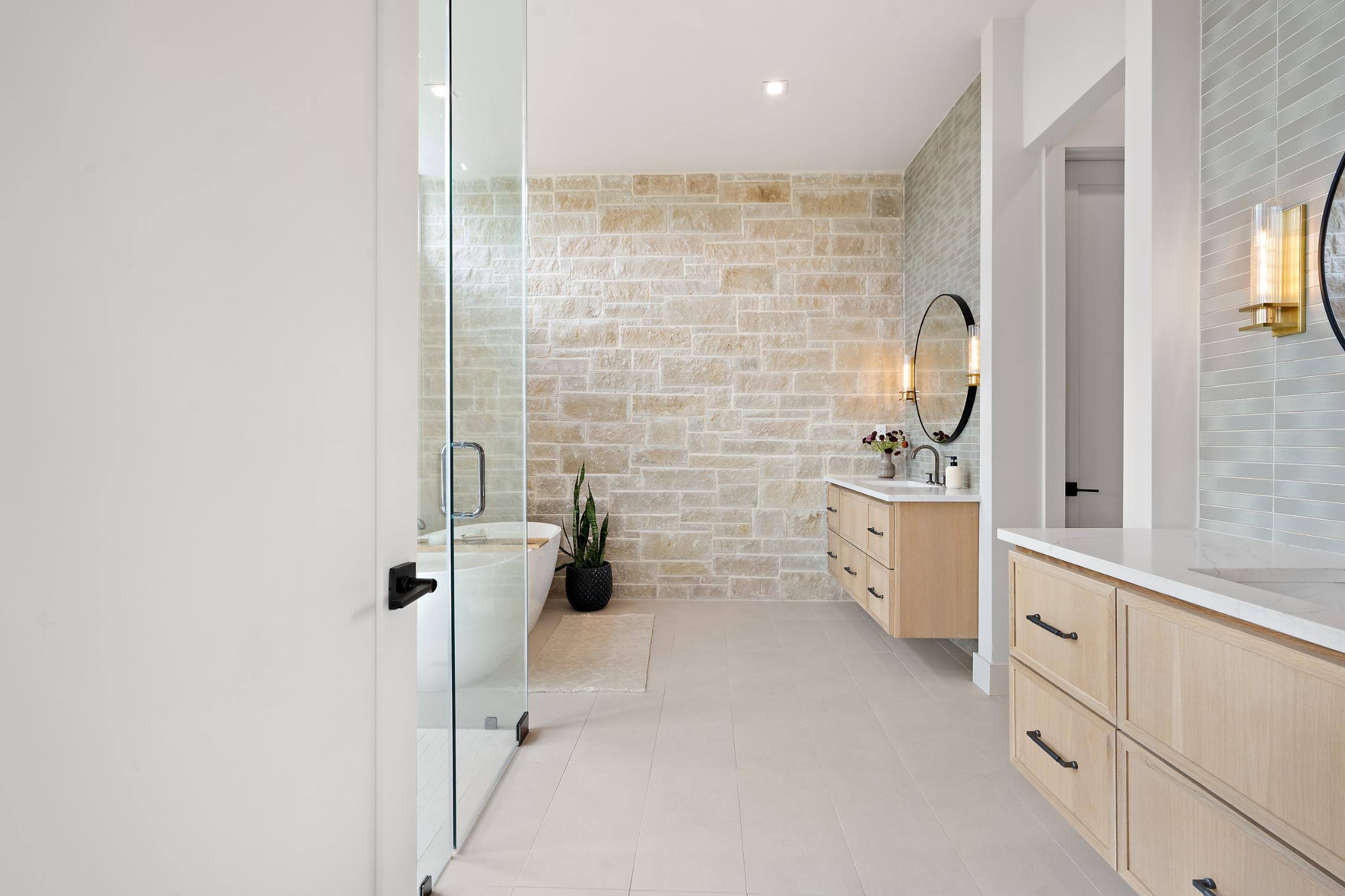 Master bathroom featuring brick walls, two sink areas, walk-in shower and free standing bathtub in custom home built in Austin, TX by J. Angelo Design Build