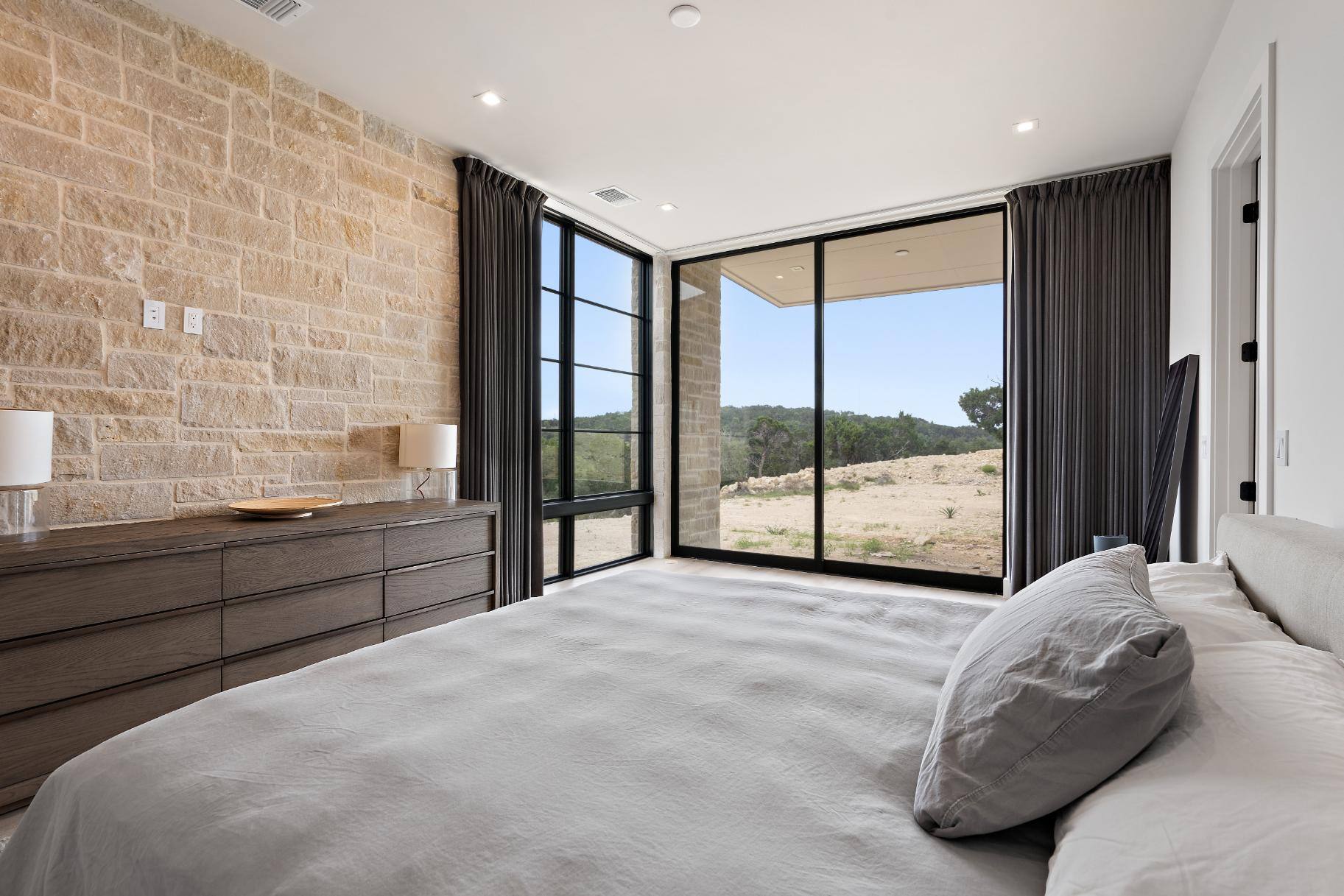 Master bedroom featuring floor-to-ceiling windows and brick wall in custom home built in Austin, TX by J. Angelo Design Build