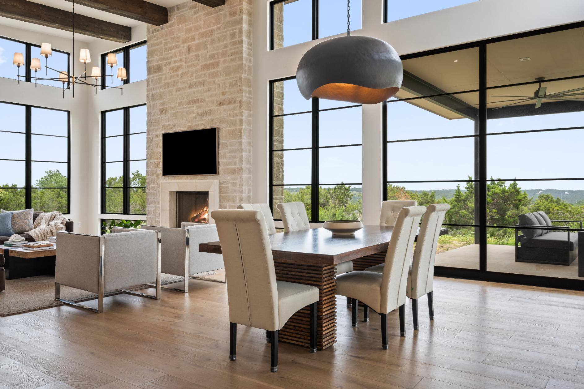 Modern living room with a stone fireplace and large windows in a custom home by J. Angelo Design Build in Southwest Austin, TX