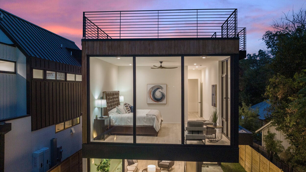 Aerial exterior photo of primary bedroom featuring floor to ceiling windows and rooftop access of custom home by J. Angelo Design Build in Austin, TX