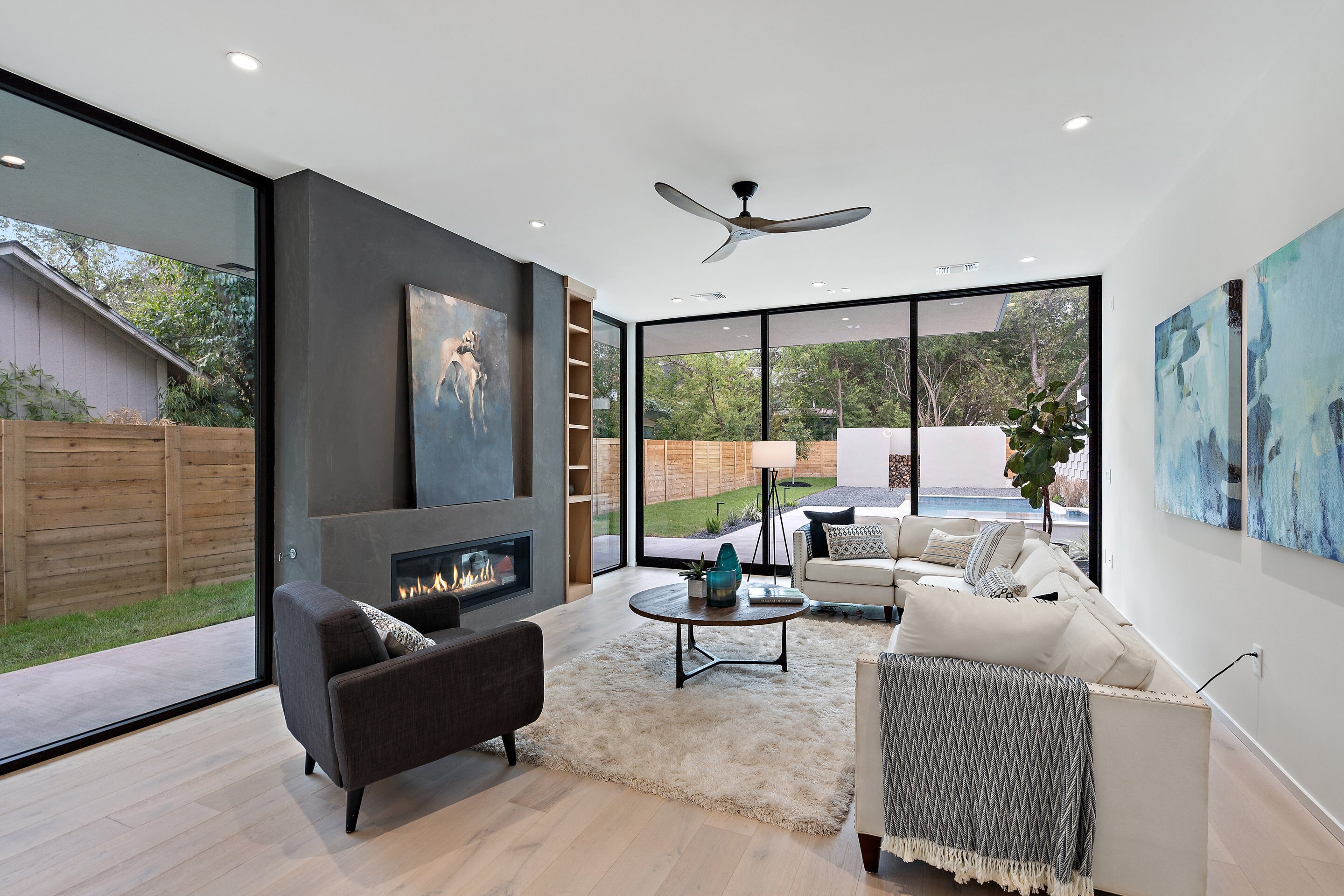 Airy and bright living room featuring floor to ceiling windows and access to backyard and pool by J. Angelo Design Build in Austin, TX