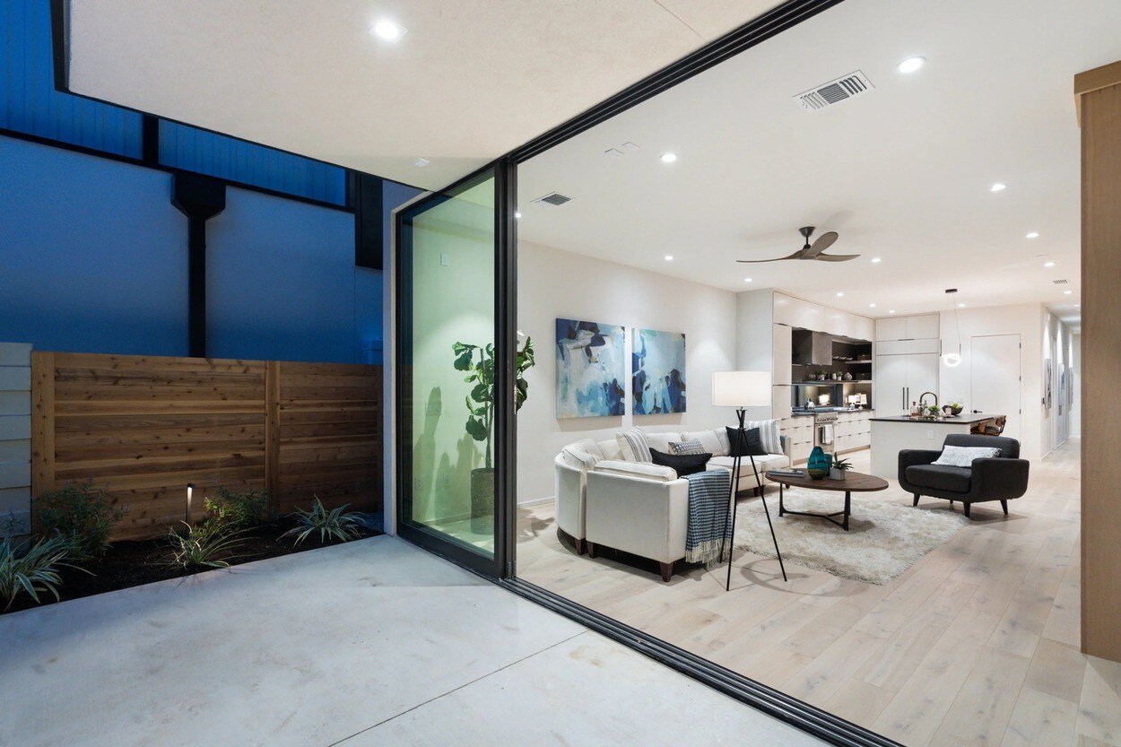 Exterior view of interior living room and kitchen from the backyard patio of custom home by J. Angelo Design Build in Austin, TX