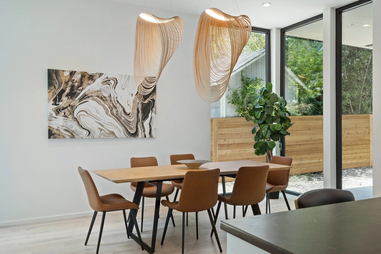 Kitchen dining area featuring statement chandelier and floor to ceiling windows by J. Angelo Design Build in Austin, TX