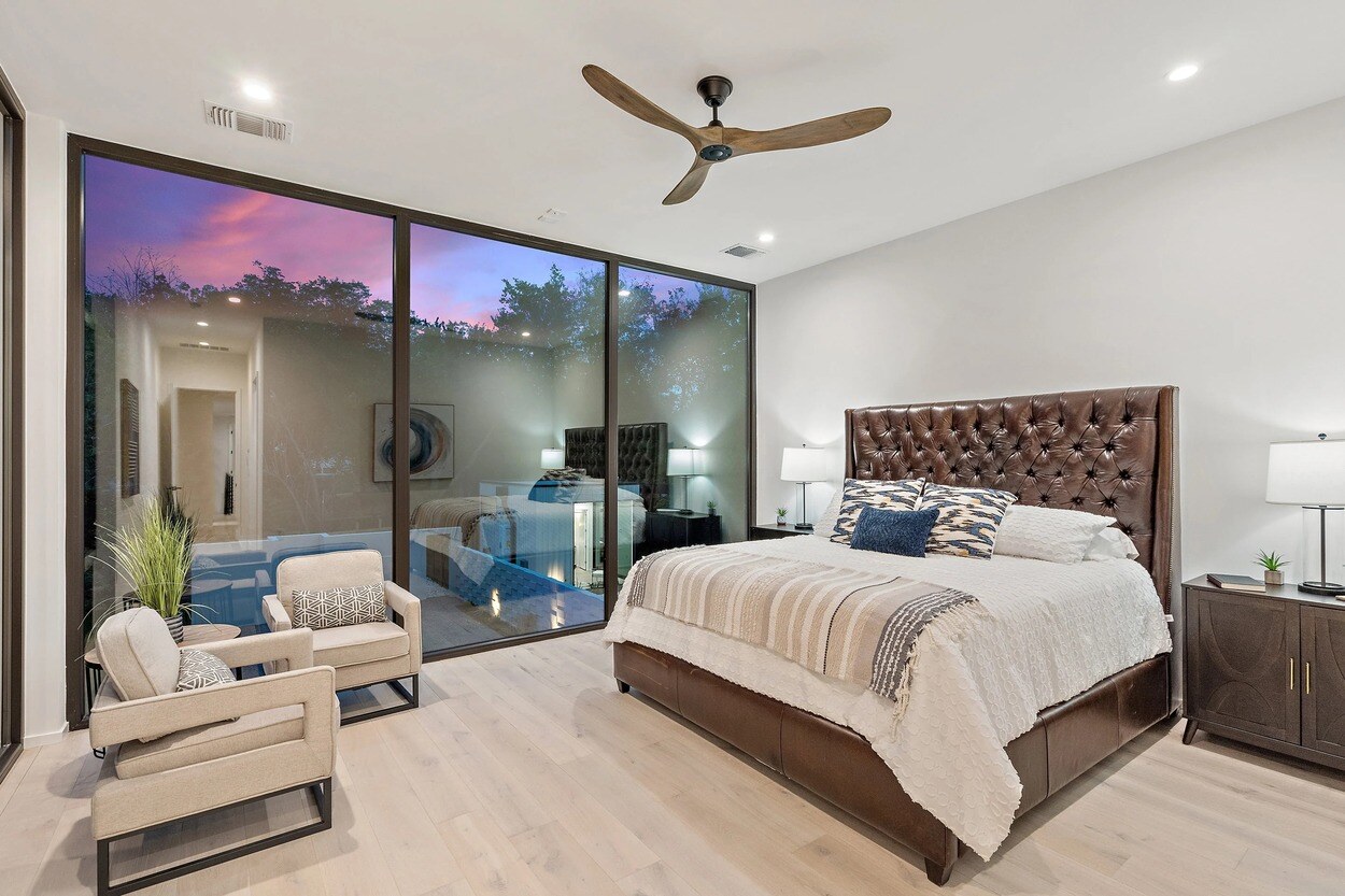 Primary bedroom featuring floor to ceiling windows in custom home by J. Angelo Design Build in Austin, TX