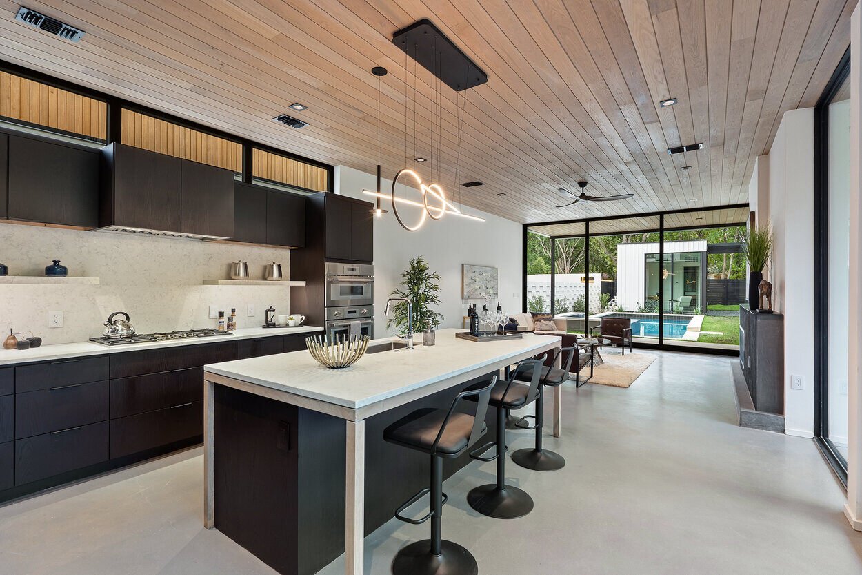 Custom kitchen featuring statement lighting and dark wood cabinetry in custom home by J. Angelo Design Build in Austin, TX