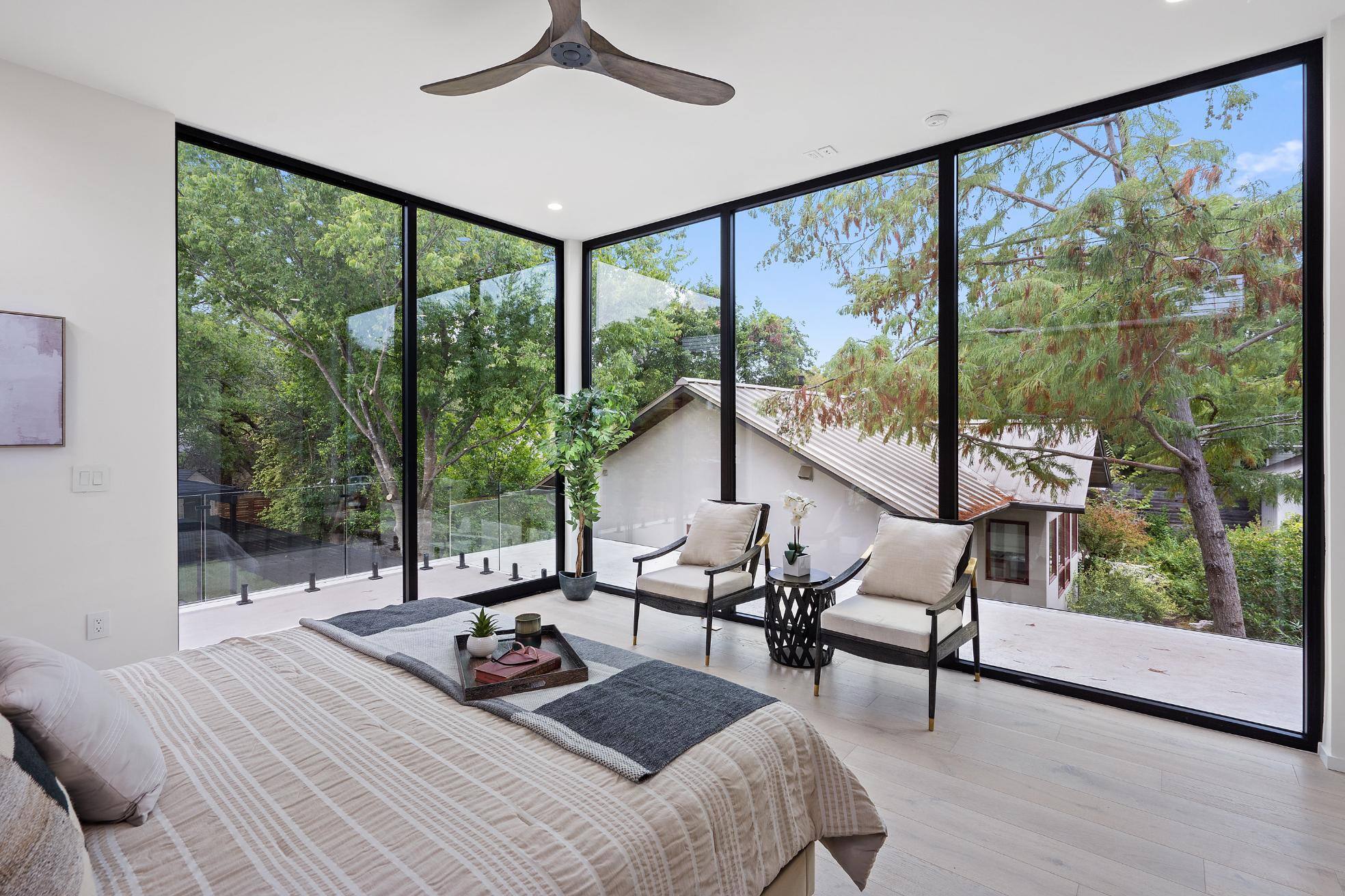 Primary bedroom with floor to ceiling windows and sitting area in custom home in Austin, TX by J. Angelo